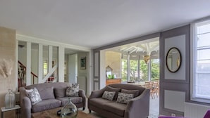 Un salon spacieux avec deux canapés, une table basse et un coin repas visible à travers une porte ouverte.