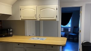 Una cocina con armarios blancos, encimera de madera y microondas.