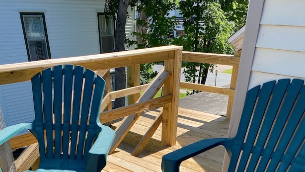 Dos sillas Adirondack azules sobre una terraza de madera con barandilla de madera.