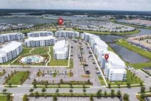 An aerial view of a modern residential complex with multiple apartment buildings, a central courtyard, and a marina. - Lovely Storey Lake Brand New Apt 3111 ( Free Water Park!!!) (Kissimmee)