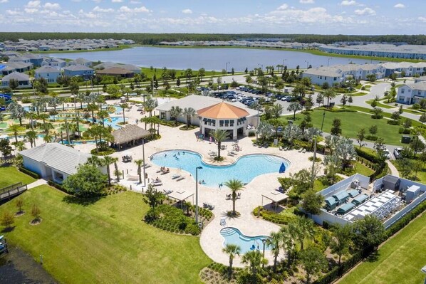 Un resort con varias piscinas, un edificio central y vistas del agua circundante y otros edificios.