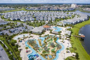 Vista aérea de una zona residencial con piscina central, rodeada de casas y una calle.