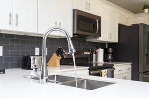 Una cocina moderna con un lavamanos de acero inoxidable, un microondas y un refrigerador.