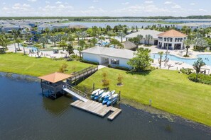 A resort with a dock, swimming pools, and a large building with a red roof.