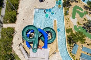 A water park with a large water slide, a pool area, and a sandy beach. - Lovely Storey Lake Brand New Apt 3111 ( Free Water Park!!!) (Kissimmee)