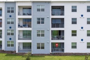 A multi-story residential building with balconies, large windows, and a red location marker on the facade. - Lovely Storey Lake Brand New Apt 3111 ( Free Water Park!!!) (Kissimmee)