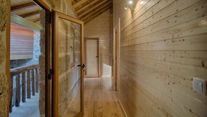A wooden interior hallway with a wooden door and a stone wall.
