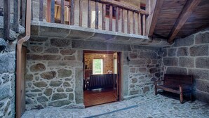 A stone-walled room with a wooden bench, a stone floor, and a wooden ceiling.