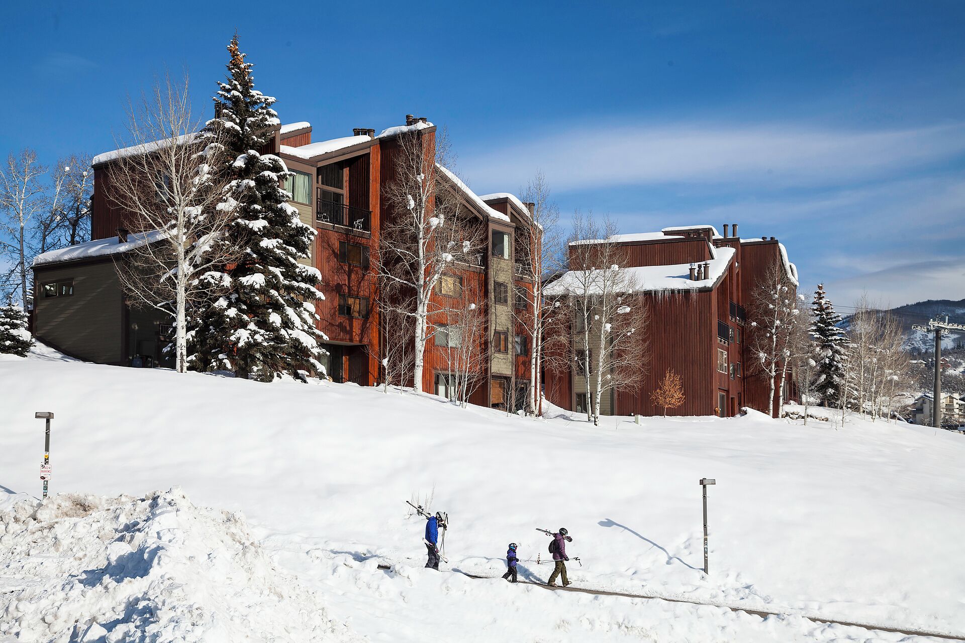A modern building with multiple floors, large windows, and a sloped roof covered in snow.