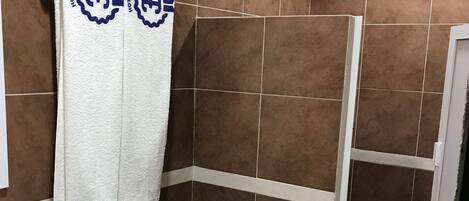 A bathroom with a toilet, sink, shower, and two towels hanging on the wall.