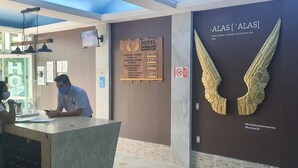 A hotel reception desk with a wooden sign listing room rates and amenities.