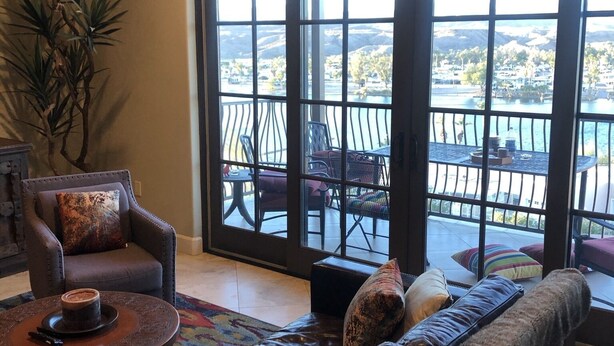 A spacious living room with a large window offering a view of a balcony and a scenic landscape.