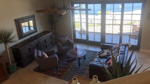 A spacious living room with a fireplace, comfortable seating, and a large window overlooking a balcony.