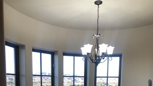 A dining area with a round table, chairs, and a view of a lake and mountains through large windows.
