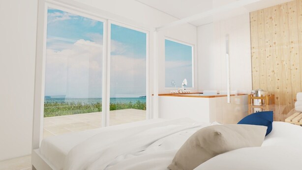 Un dormitorio moderno con una cama grande, una mesita de noche de madera, un escritorio pequeño y vista al mar.