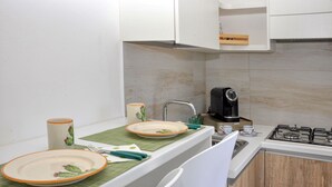 Una cocina moderna con armarios blancos, una estufa a gas, una cafetera y un mantel individual verde.