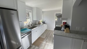 A modern kitchen with white cabinetry, a stainless steel refrigerator, a sink, and a coffee maker. - 4th Street - Close to Downtown, Newly Renovated, Walk to Shopping, Dining, Drinks (Bend)