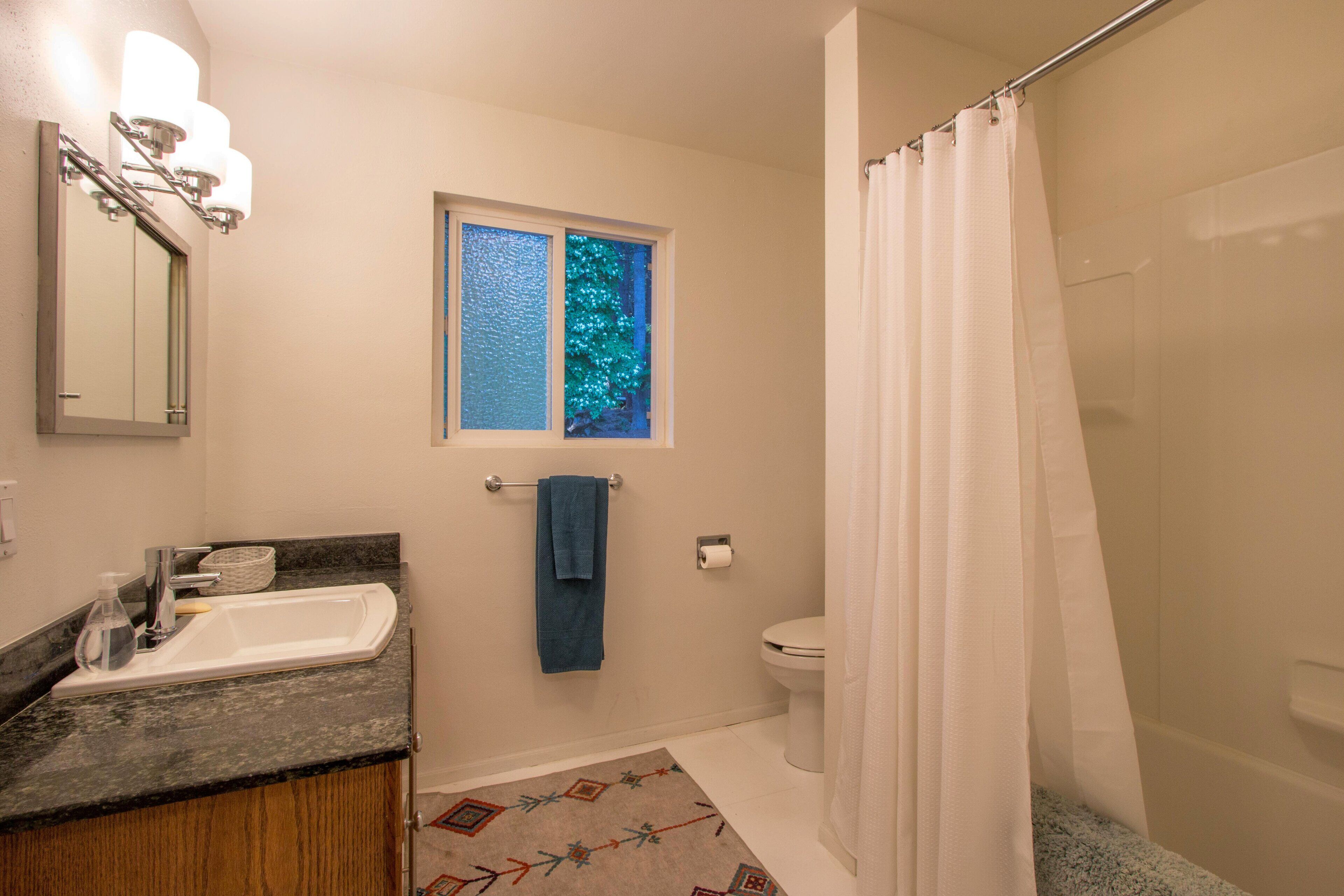 A bathroom with a sink, toilet, and shower curtain.