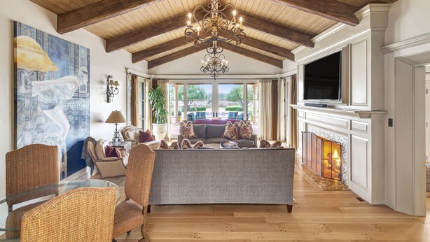 A spacious living room with a high wooden ceiling, a chandelier, a fireplace, and a large window overlooking a balcony. - Luxury Villa: Pool, Hot Tub, Pickleball, Ping-Pong & Bocce. 10 min to downtown! (Paso Robles)