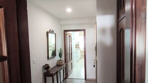 Un corridoio con una porta in legno, uno specchio e un piccolo tavolo con una pianta.