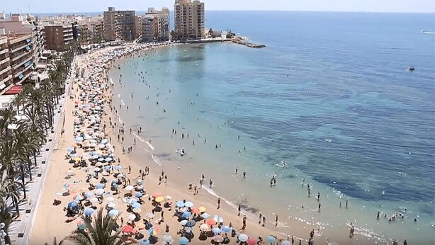 Una spiaggia con molti ombrelloni e persone.