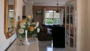 A hallway with a marble floor, a wooden dresser with a vase of flowers, a mirror, and a door leading to another room. - Beautiful property located in a private domain with indoor and outdoor pool. (Draguignan)