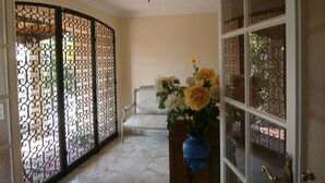A room with a white chair, a blue vase with flowers, and a decorative screen with intricate patterns. - Beautiful property located in a private domain with indoor and outdoor pool. (Draguignan)