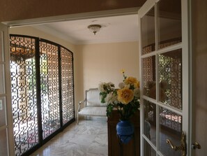 A room with a white chair, a blue vase with flowers, and a decorative screen with intricate patterns. - Beautiful property located in a private domain with indoor and outdoor pool. (Draguignan)