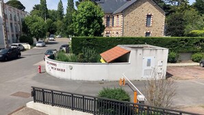 Ein Parkplatz mit einer weißen Mauer, auf der 'LES JARDINS DE LA BAULE' steht, einem roten Feuerhydranten und einem schwarzen Metallzaun.