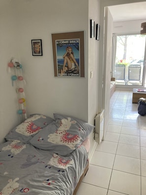 Une chambre à coucher avec un lit, une affiche accrochée au mur et une vue sur l’extérieur.