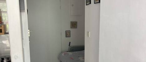 Ein Schlafzimmer mit einem Bett, einem Heizkörper, einer Tür und einem Fliesenboden.