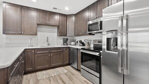 A modern kitchen with dark wood cabinets, stainless steel appliances, and a light wood floor. - Oceanfront views, amenities, all new luxury accommodations in popular Cherry Grove (North Myrtle Beach)