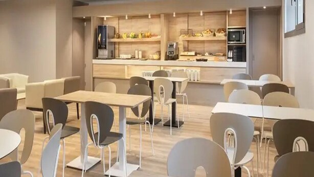 Un espace repas moderne comprenant plusieurs tables et chaises, un comptoir où sont servis des plats et des boissons, et un four à micro-ondes.