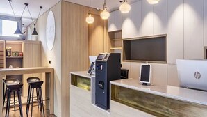 Un espace d’accueil moderne, avec un comptoir en bois, des tabourets de bar, une caisse enregistreuse et un ordinateur portable.