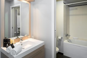 Une salle de bain moderne avec un lavabo blanc, un miroir et une baignoire.