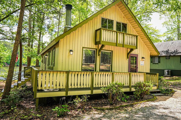 A wooden cabin with a balcony, a chimney, and a porch.