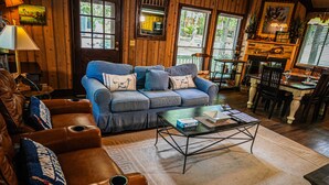 Ein gemütliches Wohnzimmer mit einem blauen Sofa, braunen Ledersesseln, einem Couchtisch und einem Kamin.