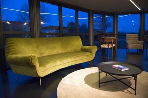 A modern living room with a green sofa, a round coffee table, and a view of the night sky through large windows. - Agriturismo Le Due Ruote (Grosseto)