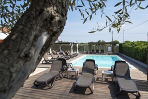 Zona junto a la piscina con sillones de descanso y una piscina.