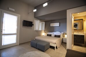 Un dormitorio con cama, mesitas de noche, televisor y baño con espejo.