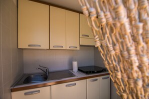 A kitchen with beige cabinets, a stainless steel sink, and a wooden countertop.