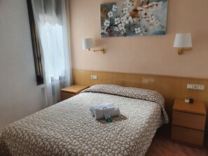 A hotel room with a bed, two bedside tables, a nightstand, a painting of flowers, and a window with curtains. - Rio de Castro (Barcelona)