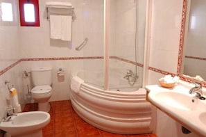 A bathroom with a bathtub, a sink, a toilet, and a bidet. - El Cruce (Manzanares)
