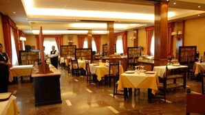 A restaurant with multiple tables, some with yellow tablecloths, and a polished marble floor. - El Cruce (Manzanares)