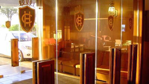 A hotel entrance with glass doors, a reception desk, and seating area visible through the glass. - El Cruce (Manzanares)