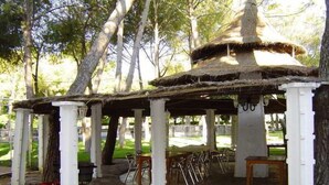 A gazebo with white columns and a thatched roof, surrounded by trees. - El Cruce (Manzanares)