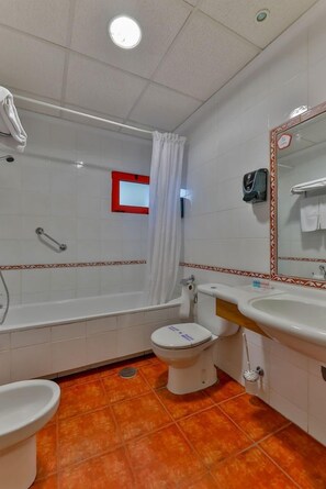 Un baño con bañera, inodoro, bidé y lavamanos.