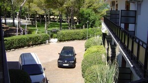A parking area with a car, a white van, and a building with air conditioning units. - El Cruce (Manzanares)