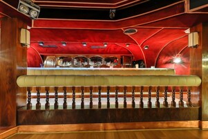 Una zona de bar con mostrador, asientos acolchados y techo rojo.