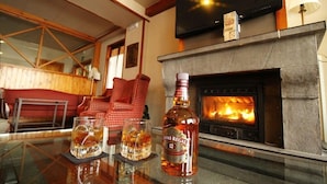 A bar area with a fireplace, a bottle of Chivas Regal 12, and two glasses of whiskey on a glass table. - Villa de Sallent (Sallent de Gallego)